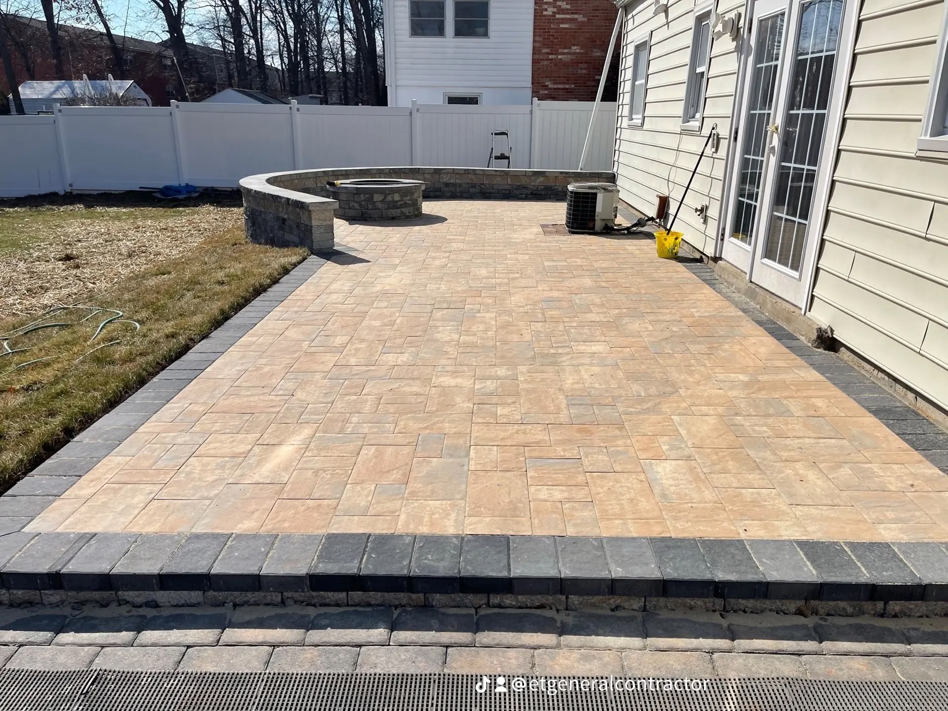 Paver patio with fire pit and stone seat wall built by E.T. General Contractor